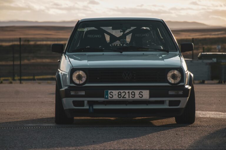 Front view of a classic Volkswagen Golf MK2 on a racetrack at sunset.