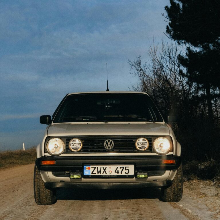 Classic Volkswagen Golf Mk2 captured on a dirt road under clear sky background.