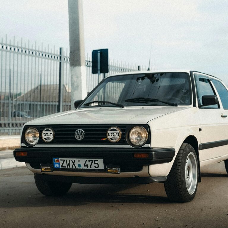 Classic white Volkswagen Golf parked on a city street, showcasing vintage design elements.